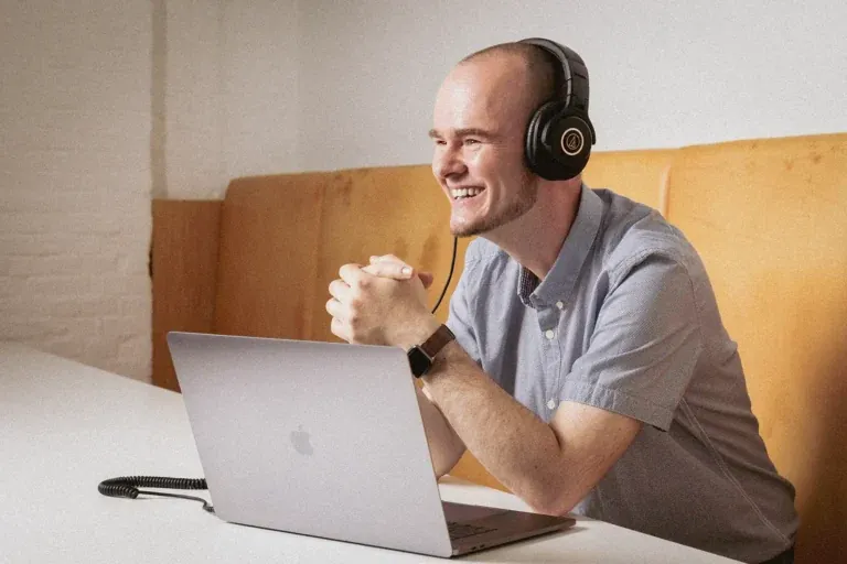 Adobe-Mitarbeiter Nico Becherer mit Kopfhörern sitzt vor einem MacBook in einem modernen Hamburger Büro, fotografiert von Frank Erpinar