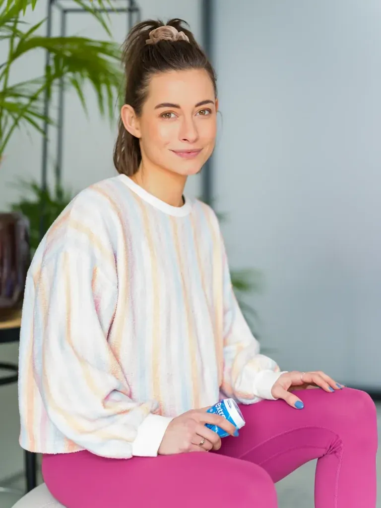 Jennifer Lange sitzt entspannt in buntem Streifenpullover und pinker Leggings und hält eine blaue Dose Wrigley's Extra in der Hand, fotografiert von Frank Erpinar