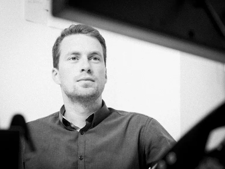 Schwarz-Weiß-Portrait eines Mitarbeiters der Skuld Germany GmbH mit konzentriertem Blick am Schreibtisch, fotografiert von Frank Erpinar